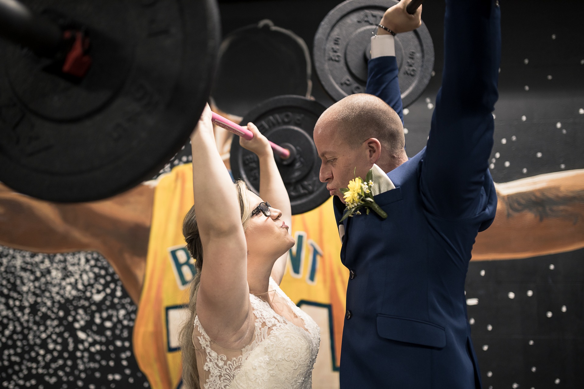 Svatební fotograf Kladno - ženich a nevěsta v posilovně zvedají činky nad hlavu